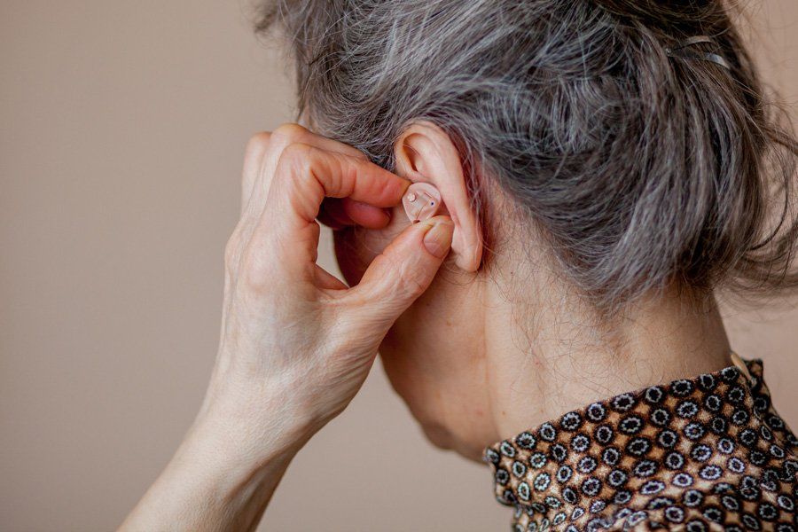 Femme âgée mettant en place sa protection antibruit dans les oreilles