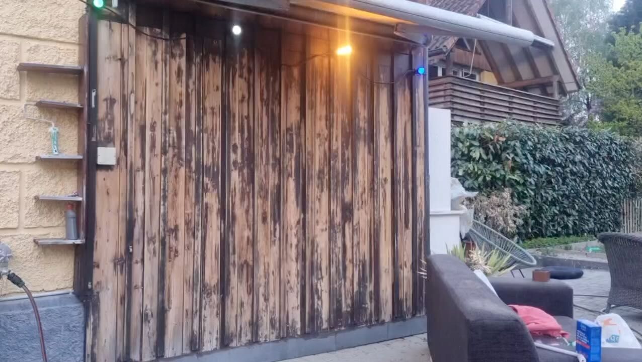 Eine Holzwand mit einem Sofa und Stühlen davor. Foto von GrünEcke