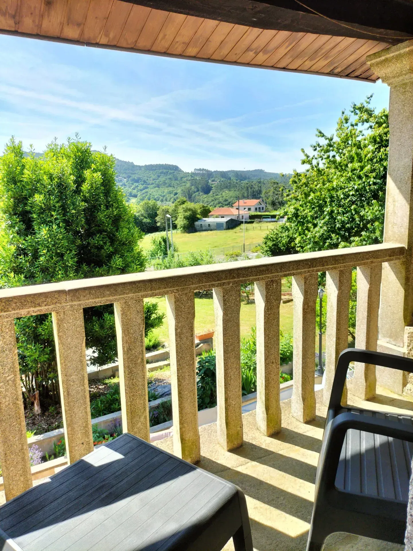 Un balcón con vista a un campo y árboles.