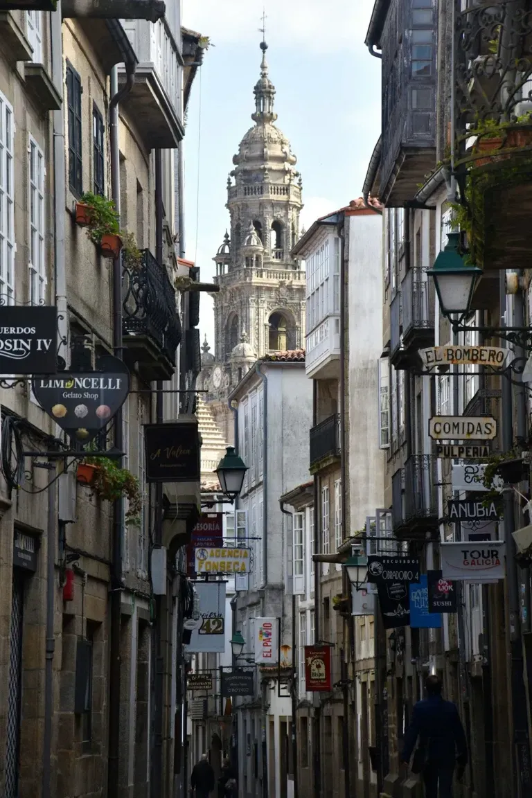 Una calle estrecha con una torre de reloj al fondo