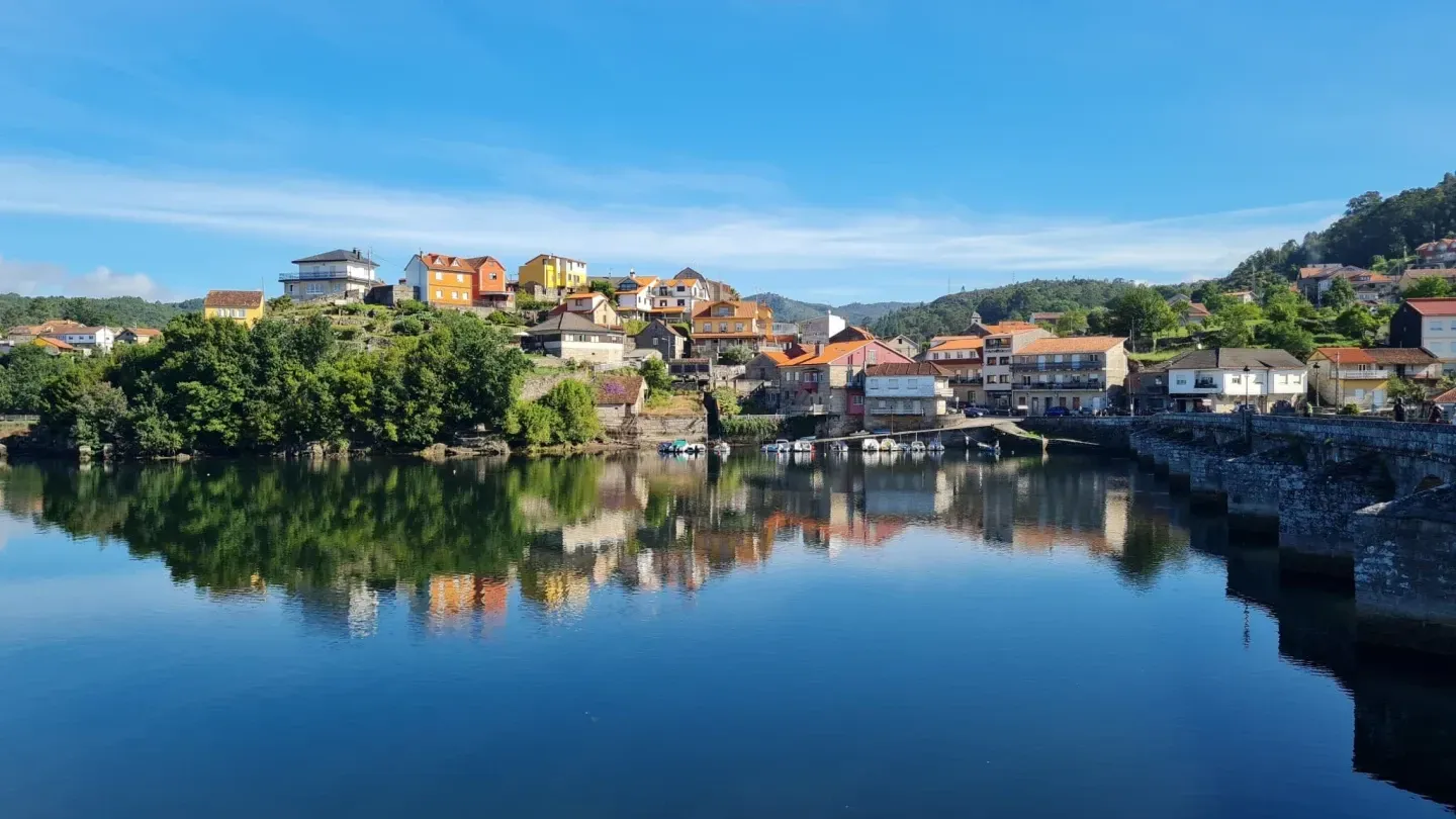 Un pequeño pueblo se refleja en el agua de un río.