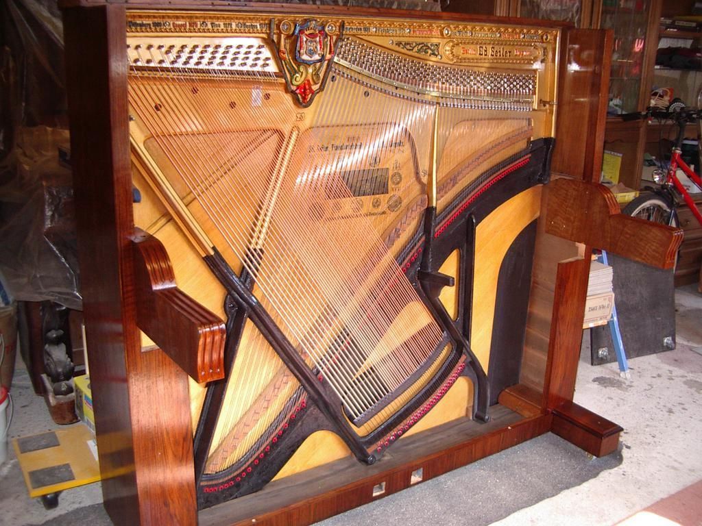 Klavierrahmen mit Saiten, Resonanzboden sichtbar. Mahagonirahmen. Innen sind Saiten und Zierelemente zu sehen.