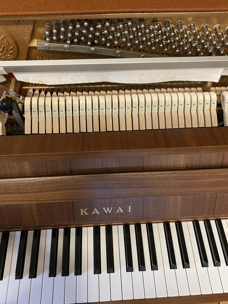 Innenansicht eines Kawai-Klaviers mit sichtbaren Tasten, Hämmern und Saiten.