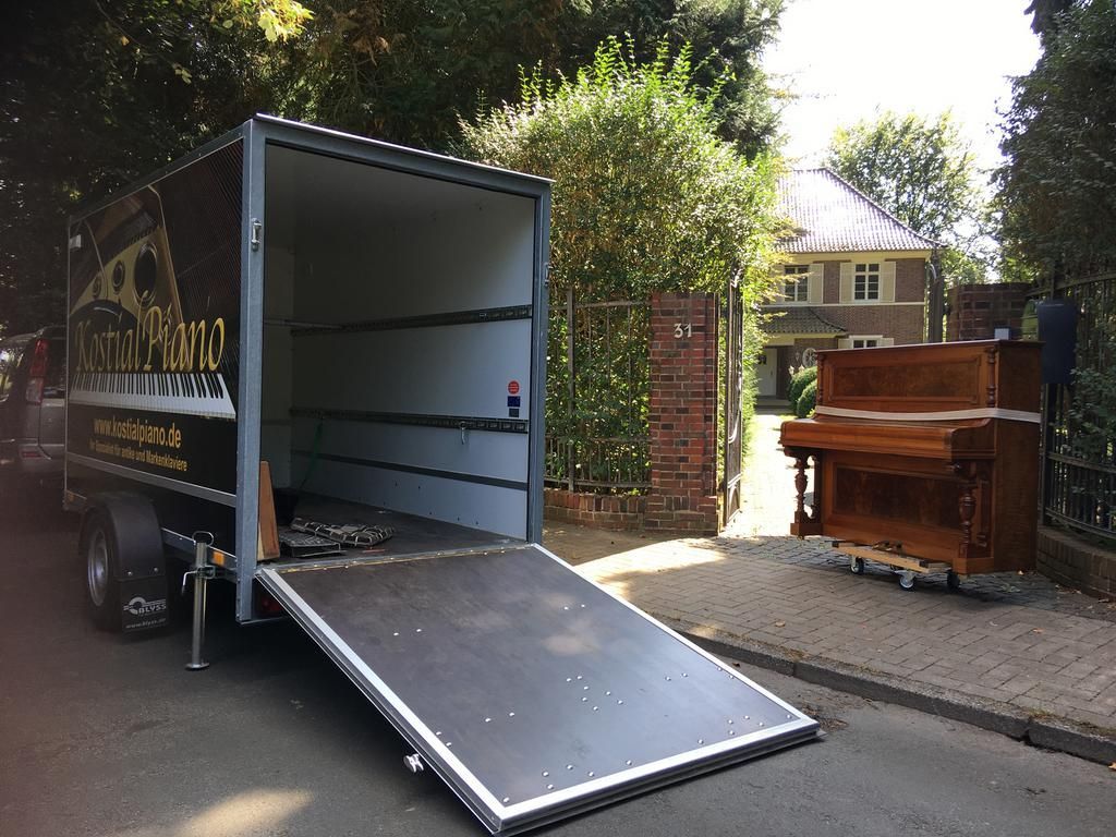 Ein Klavier wird vor einem Haus mithilfe einer Rampe auf einen Lastwagen verladen.