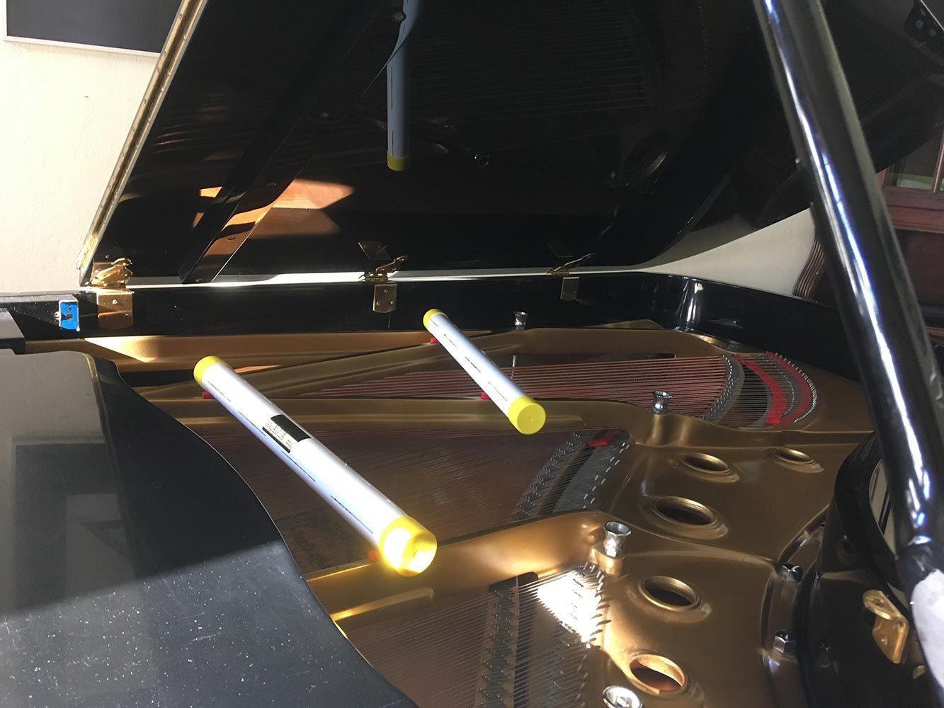 Innenansicht eines Klaviers mit Saiten, Hämmern und Resonanzboden. Zwei Marker befinden sich auf dem Resonanzboden.