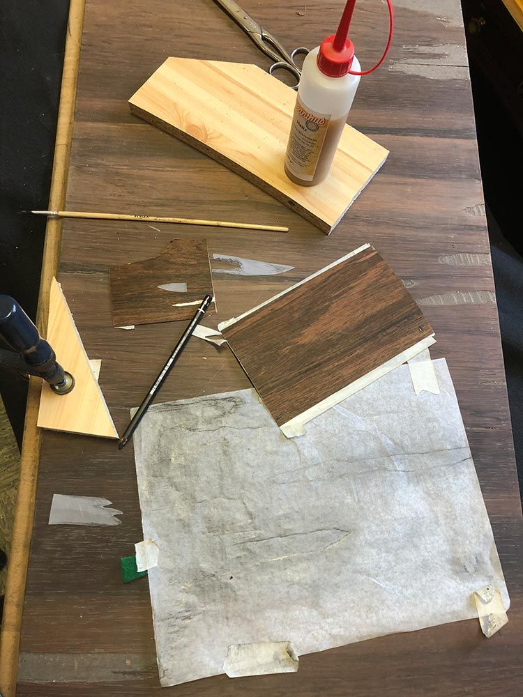 Holzbearbeitungsprojekt in Arbeit: Leim, Holzstücke, Werkzeuge auf einer dunklen Holzoberfläche.