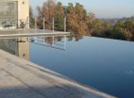 Una gran piscina está rodeada de árboles y un edificio.