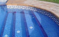 Una piscina con azulejos azules y un diseño de clave griega en el borde.