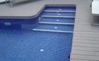 Una piscina con azulejos azules y escaleras que conducen a ella.