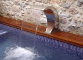 Una cascada sale del costado de una piscina.