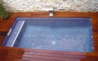 Una pequeña piscina está situada encima de una terraza de madera.