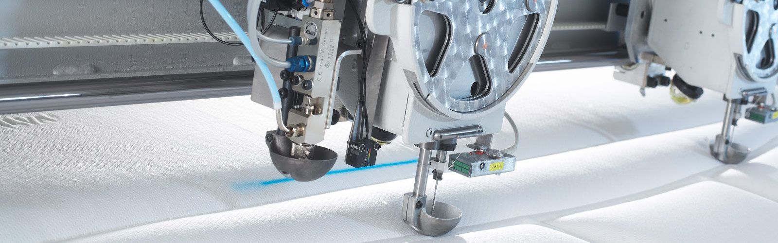 Eine Nähmaschine schneidet ein Stück weißen Stoff.