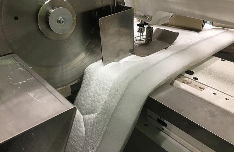 Eine Maschine schneidet ein Stück Stoff auf einem Tisch.