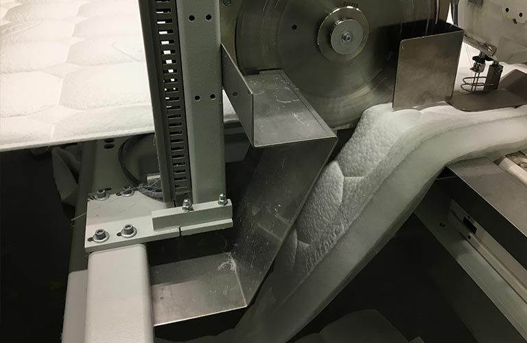Eine Maschine schneidet ein Stück Stoff auf einem Förderband.
