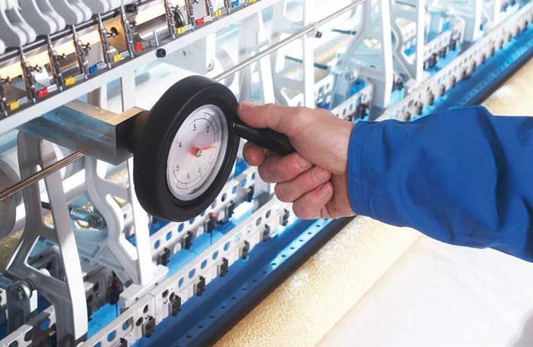 Eine Person hält ein Druckmessgerät vor eine Maschine.