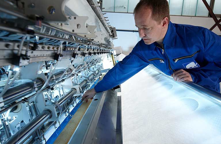 Ein Mann in einer blauen Jacke arbeitet an einer Maschine