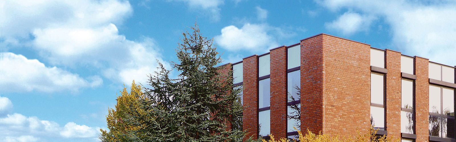 Ein Backsteingebäude mit vielen Fenstern und einem Baum davor