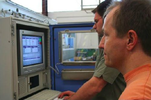Zwei Männer schauen auf einen Computerbildschirm und einer benutzt eine Maus