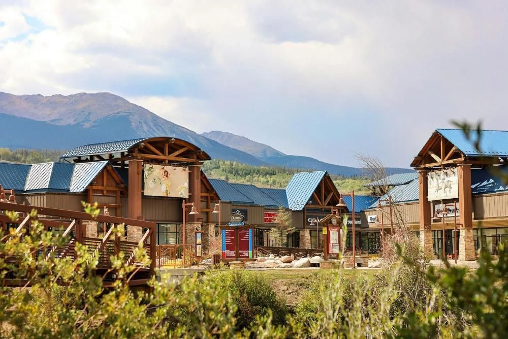 Buildings with blue roofs and brown wood accents, set against mountain backdrop.