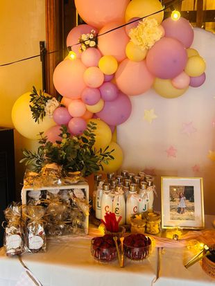 Arco de globos en tonos pastel sobre una mesa de postres decorada con regalos y flores