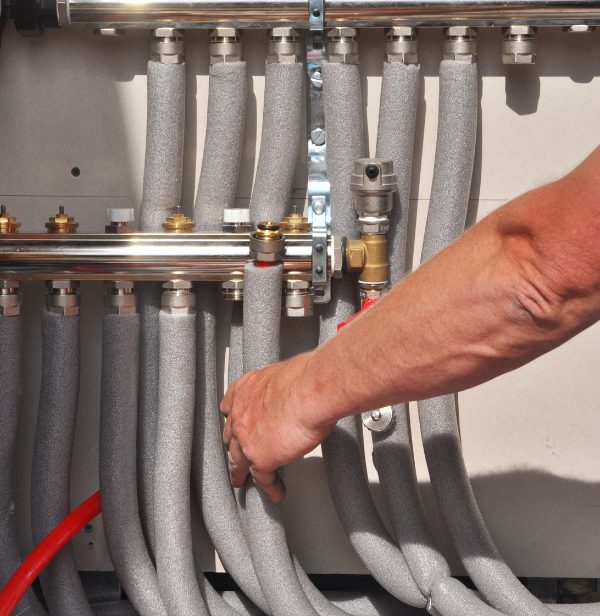 A man 's hand is reaching into a bunch of pipes