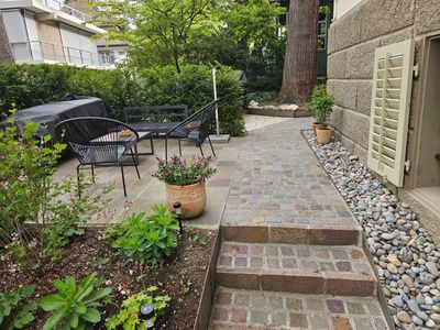 Steinstufen und gestapelte Steinmauern in einem angelegten Garten mit Bäumen und Sträuchern.