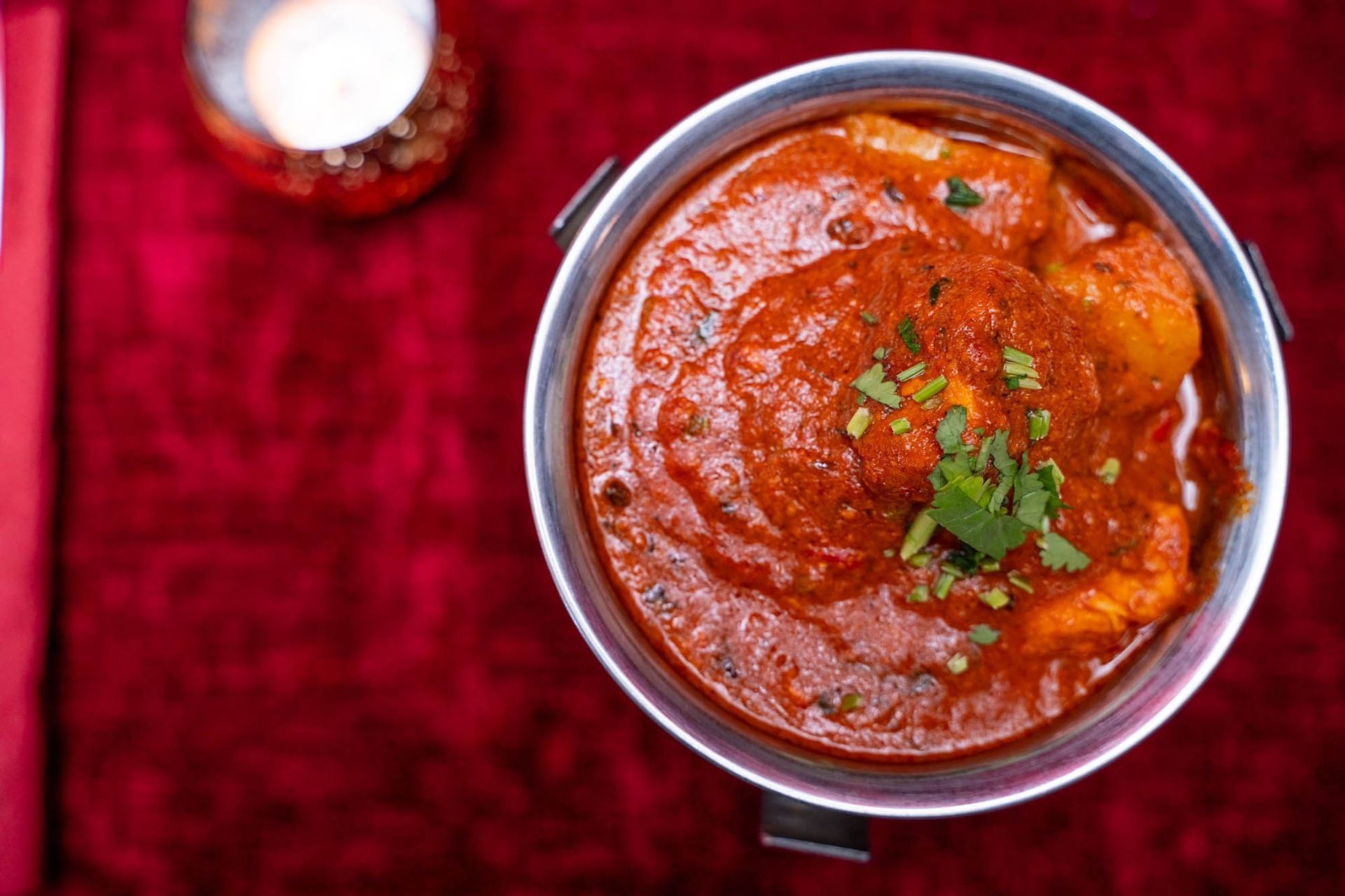 Eine Schüssel Hühnercurry auf einem roten Tischtuch.