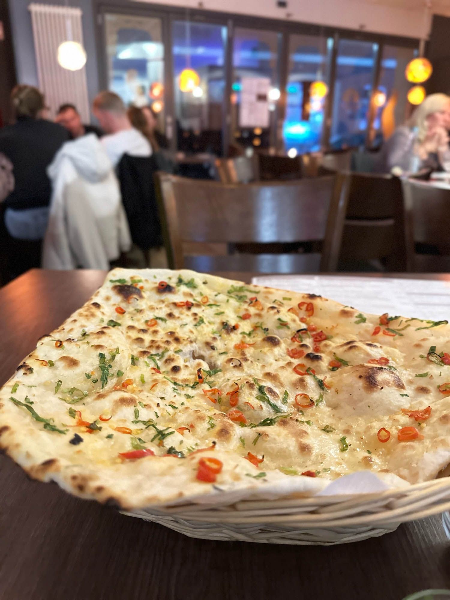 Ein Stück Naan-Brot liegt auf einem Holztisch in einem Restaurant.