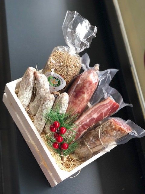 Cassa di legno contenente un assortimento di salsicce e carni artigianali con ripieno di frutti rossi e paglia.