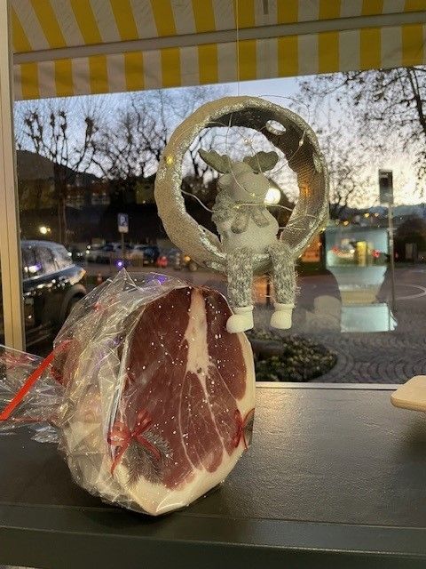 Salumi confezionati su un bancone davanti a una scultura decorativa a forma di ghirlanda e a una finestra di notte.
