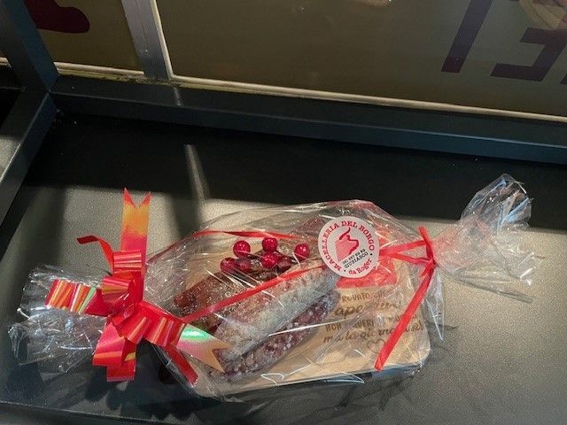 Cesto regalo incartato con nastro rosso e cioccolatini su un tavolo scuro