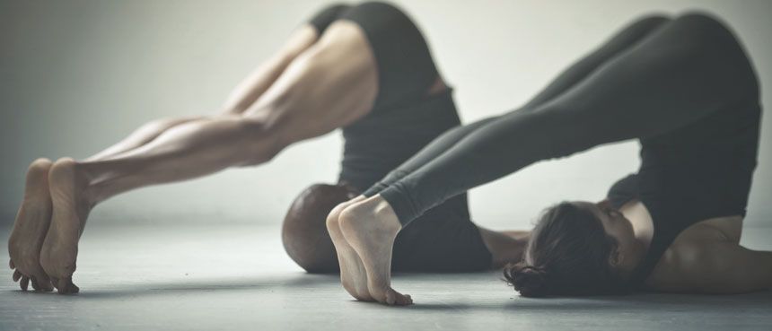 Un hombre y una mujer están haciendo ejercicios de yoga juntos.