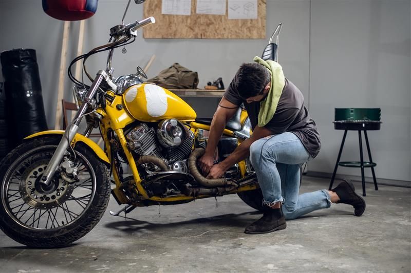 Un hombre está trabajando en una motocicleta amarilla en un garaje.