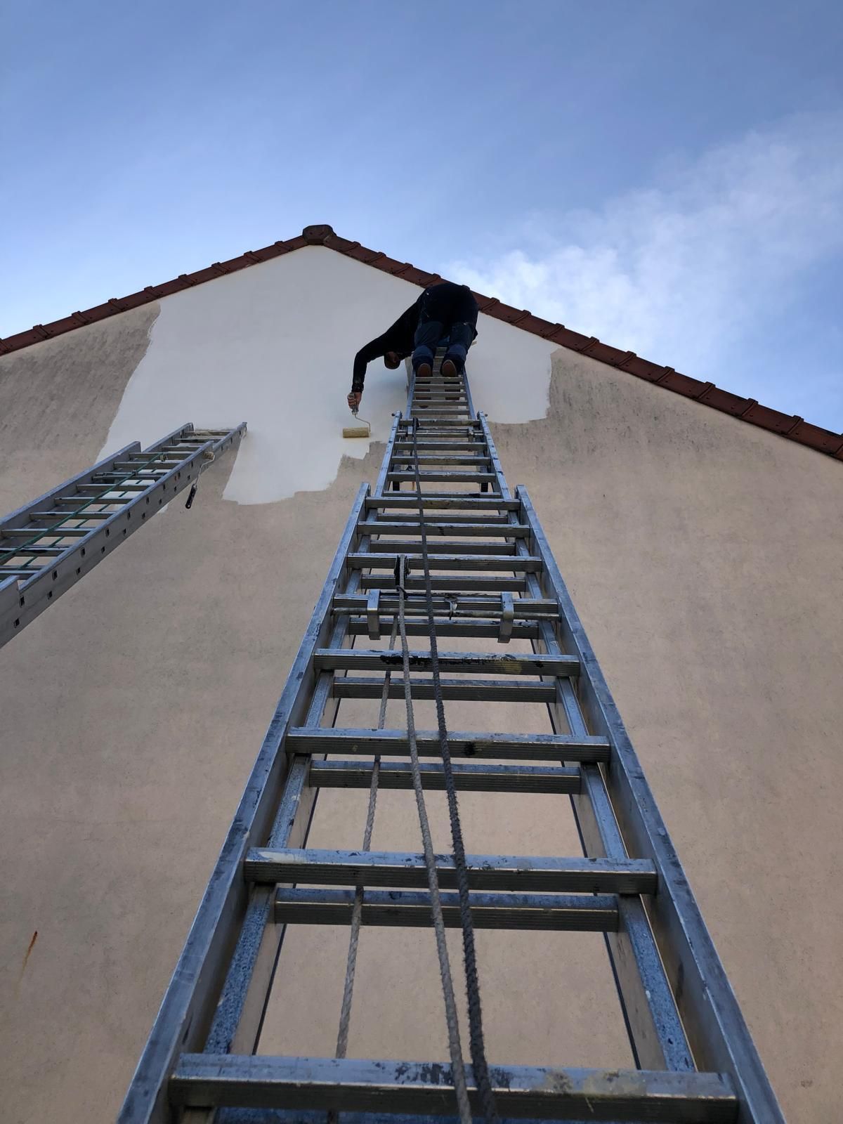 Artisan qui peint la façade d'une maison