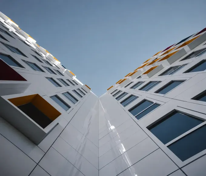 Mirando hacia arriba entre dos modernos edificios de apartamentos blancos contra un cielo azul
