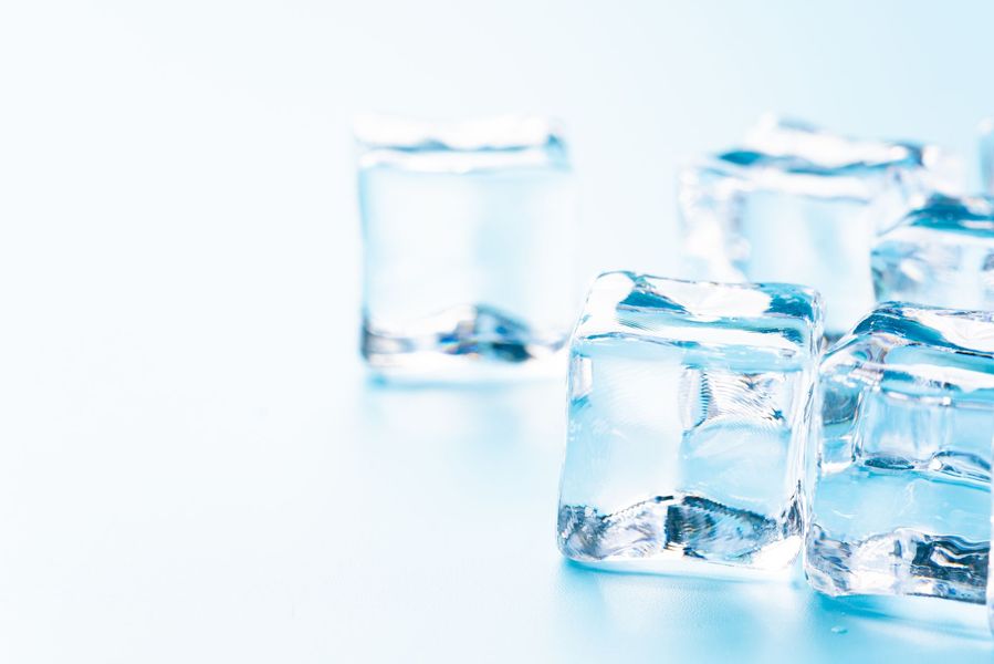 Glaçons transparents sur fond blanc, avec une teinte bleue froide