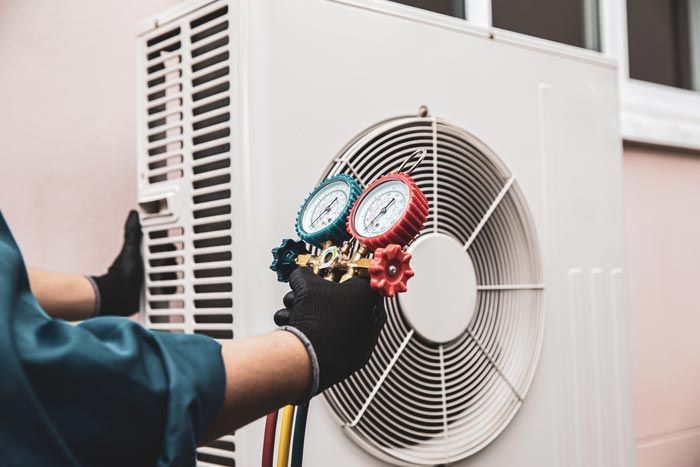 Un technicien vérifie les manomètres d'une unité de climatisation extérieure (condenseur).
