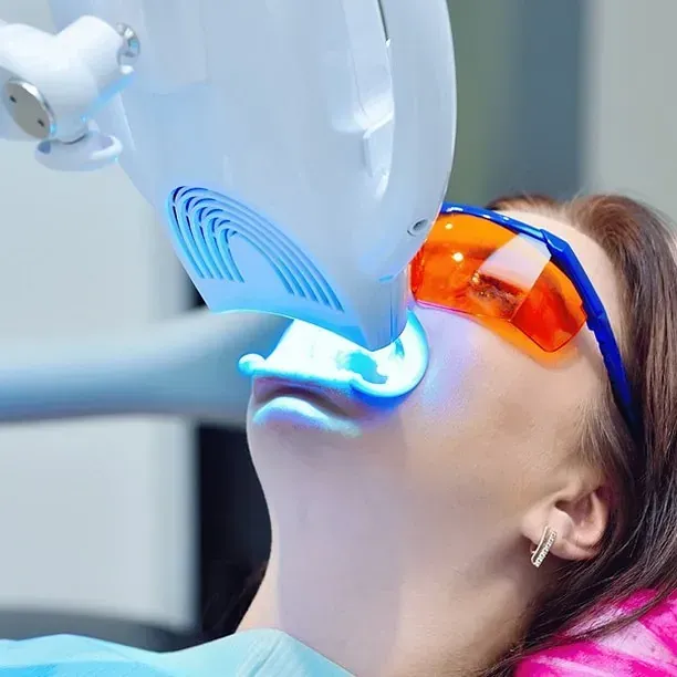 Una mujer se blanquea los dientes en un consultorio dental.