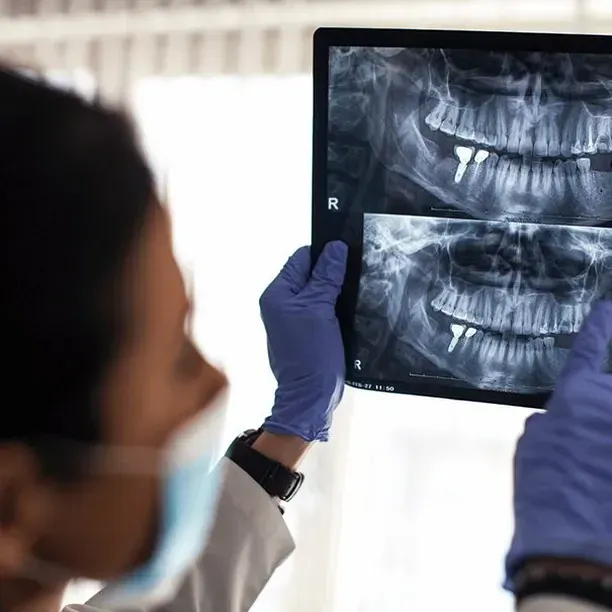 Un dentista está mirando una radiografía de los dientes de una persona.