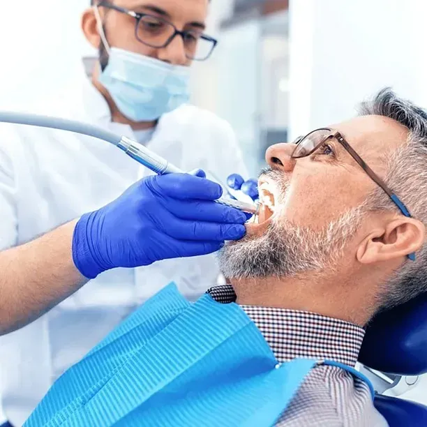 Un hombre se está haciendo examinar los dientes por un dentista.