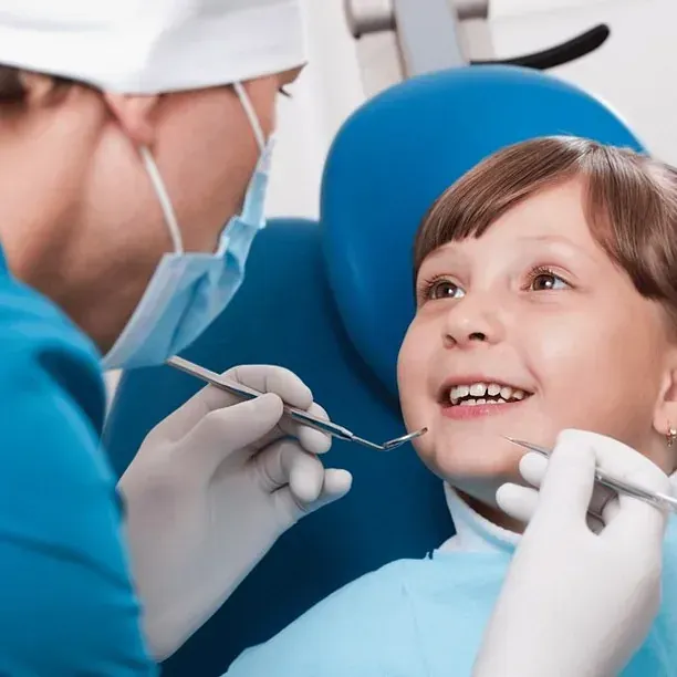 Una niña pequeña se hace examinar los dientes por un dentista.