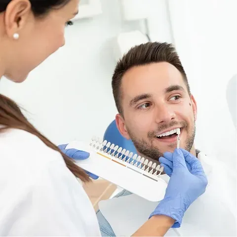 Un hombre está sentado en una silla dental mientras un dentista le examina los dientes.