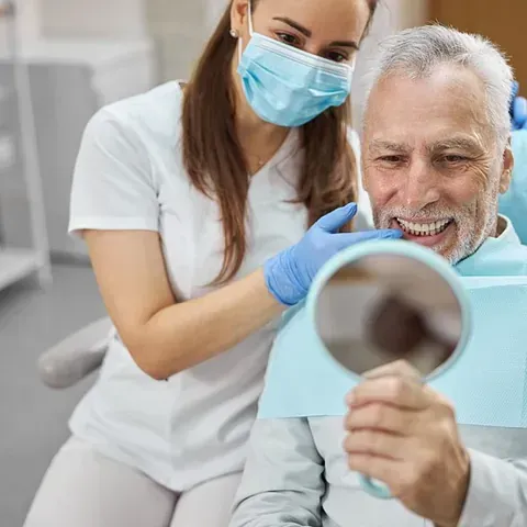 Un dentista mira los dientes de un paciente en un espejo.