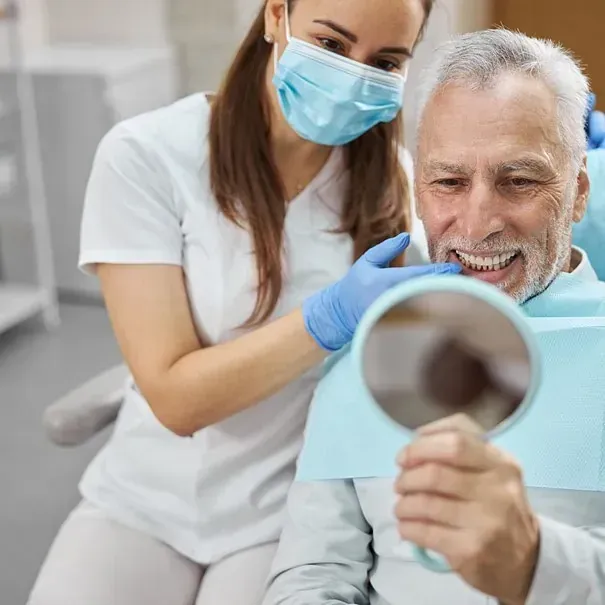 Un dentista mira los dientes de un paciente en un espejo.