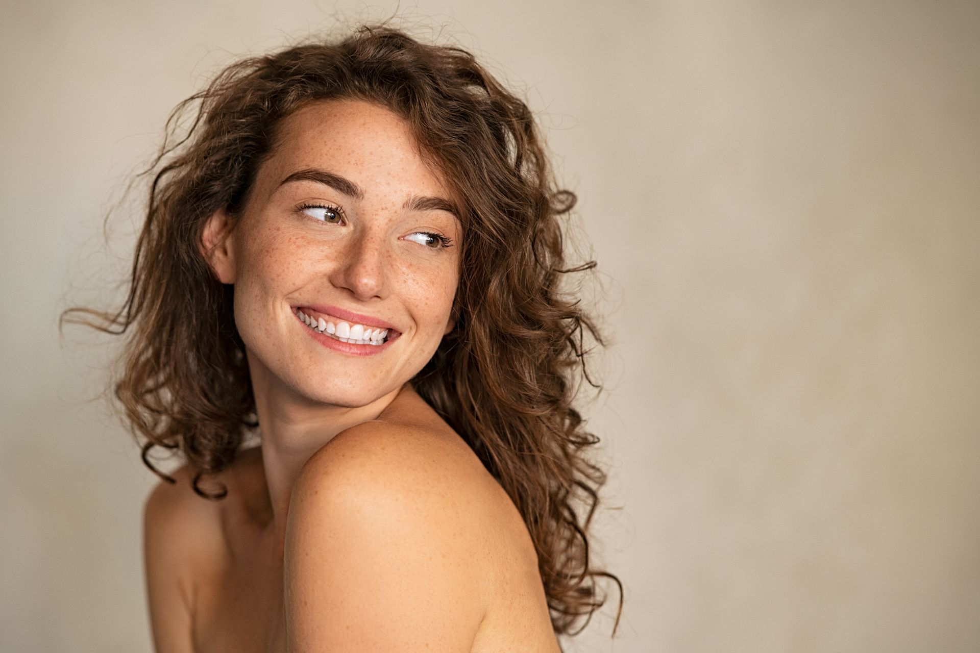 Femme aux cheveux bouclés en train de sourire