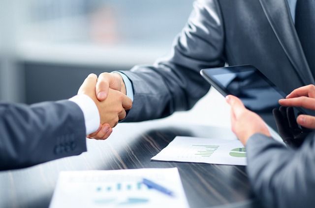 Dos personas de negocios se dan la mano sobre una mesa.