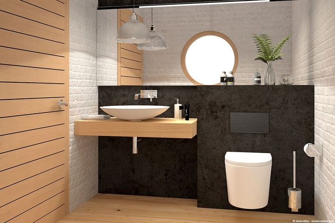 Modernes Badezimmer mit Holzakzenten, rundem Spiegel, weißem Waschbecken und Toilette vor einer dunklen Wand.