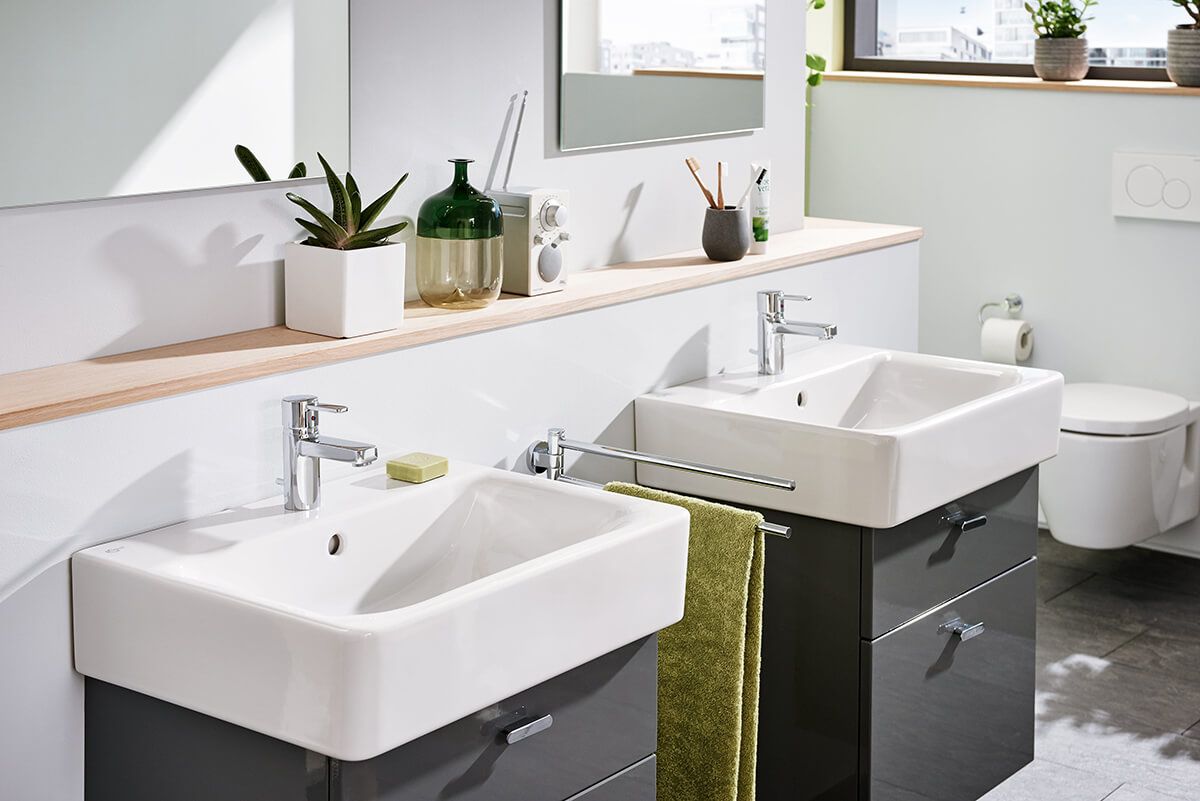 Zwei moderne Waschbecken mit grauen Schränken in einem Badezimmer.