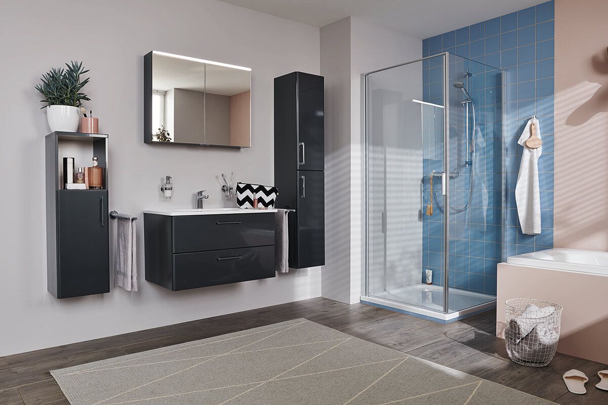 Eckdusche mit Glaswänden, Regenduschkopf, Handbrause und dunkelgrauem Boden vor hellgrauer Wand.