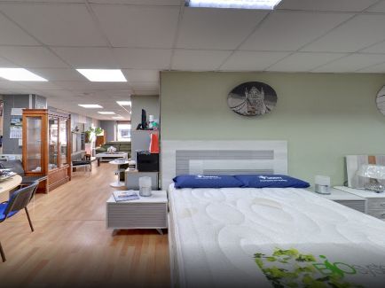 Sala de exposición de muebles de dormitorio con cama y otros muebles en exposición.